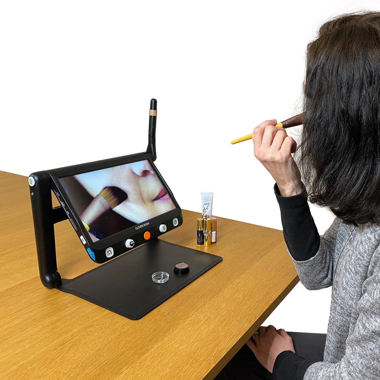 A woman putting makeup on with the self-viewing distance camera capability of the Cloverbook Plus and Pro