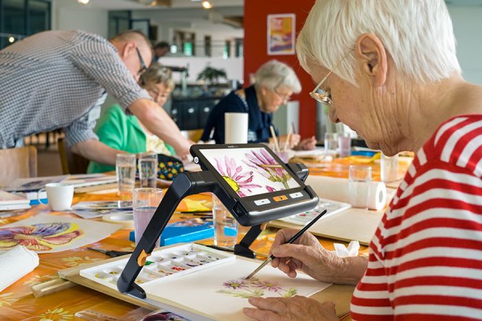 An older white woman painting below the explore 8 in its elevated stand.