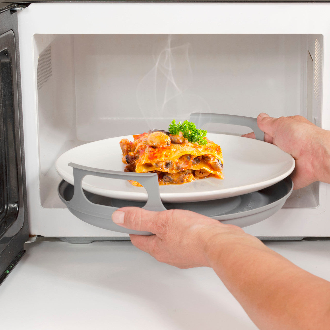 Microwave Caddy – A versatile kitchen accessory suitable for individuals with visual impairments, accommodating plates or bowls from 5 to 10 inches in diameter, providing safe handling of hot microwave dishes is sitting inside a microwave with a warm bowl of pasta and green vegetables sitting on the top, warm and ready to eat. 